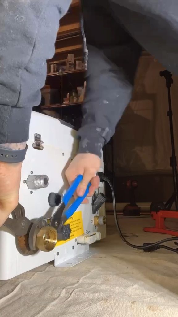 CHANNELLOCK® pliers with blue handles grip a round brass knob on a white machine panel.