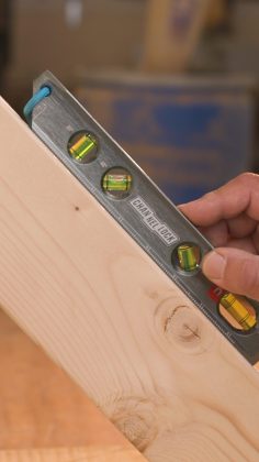 CHANNELLOCK® spirit level with a blue end cap held against a light wood plank, showing three bubble vials.